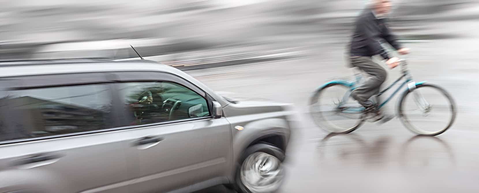 Man on bicycle about to get into a bicycle accident with an oncoming car